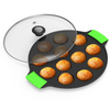Black egg roll maker with green handles and glass lid, containing golden-brown egg rolls on a white background.