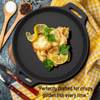 Fish dish on a black cast iron skillet with lemon slices and parsley, placed on a checkered cloth.