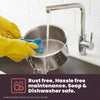 Person cleaning a metal sink with a sponge and wearing yellow gloves, with text about rust-free and soap-safe properties.