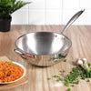 Stainless steel wok on a wooden table with vegetables and rice