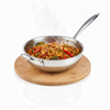 Stainless steel wok with stir-fry on a wooden trivet against a white background