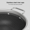 Stainless steel frying pan with rivet caps on a gray background
