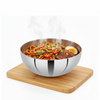 Stainless steel bowl with noodles and vegetables on a wooden board