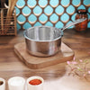 Stainless steel pot on a wooden trivet with a decorative background