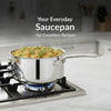 Stainless steel saucepan on a gas stove with food inside, kitchen background.
